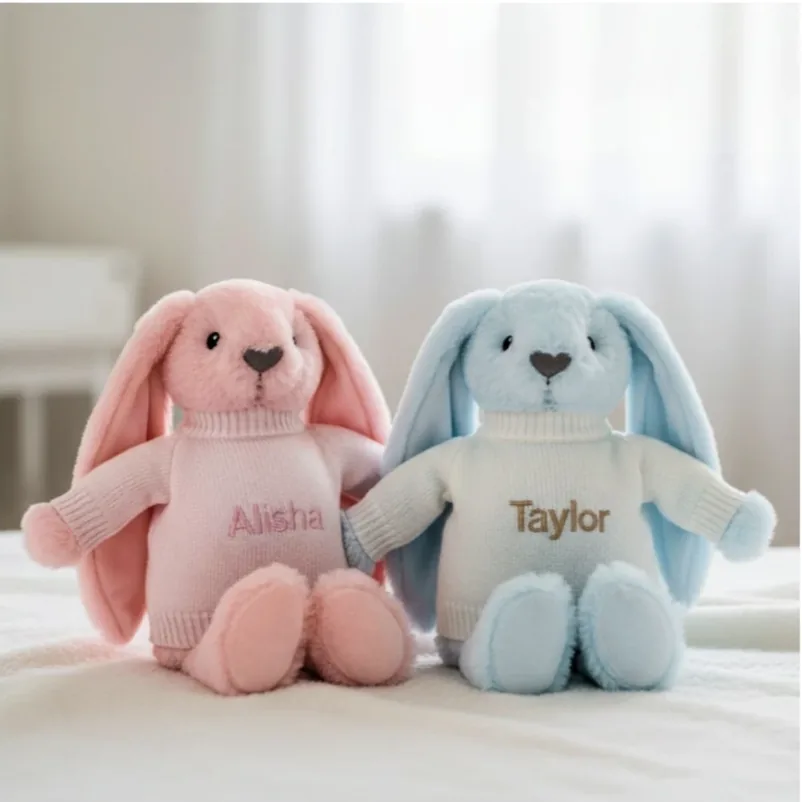 A pink bunny and a blue bunny in sweaters embroidered with names